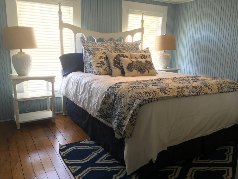 Cette image montre une petite chambre d'amis marine avec un mur bleu et un sol en bois brun.