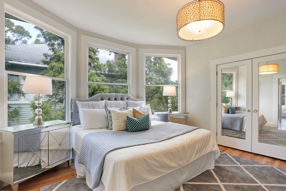 Photo of a large traditional master bedroom in Tampa with white walls and light hardwood flooring.