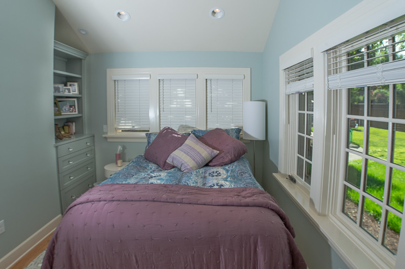 Modelo de dormitorio principal de estilo americano pequeño sin chimenea con paredes azules y suelo de madera en tonos medios