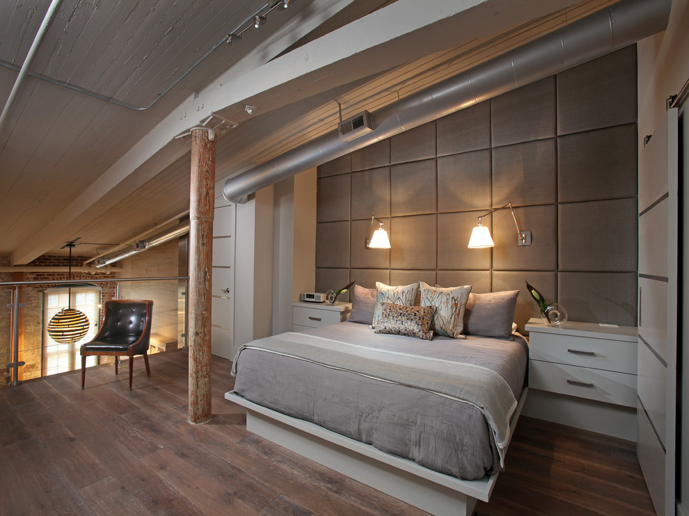 Cette photo montre une chambre mansardée ou avec mezzanine industrielle de taille moyenne avec un sol en bois brun, un mur blanc et aucune cheminée.