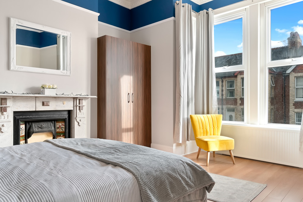 Bild på ett funkis sovrum, med blå väggar, ljust trägolv, en standard öppen spis och beiget golv