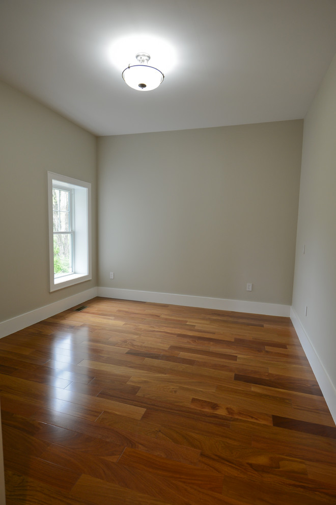 Foto på ett funkis sovrum, med grå väggar, mellanmörkt trägolv och brunt golv