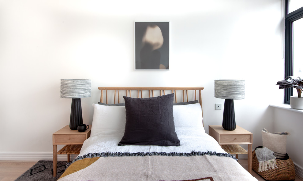 This is an example of a scandi bedroom in London with white walls, medium hardwood flooring and brown floors.