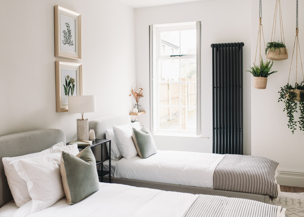 Traditional guest bedroom in Other with white walls, medium hardwood flooring and brown floors.