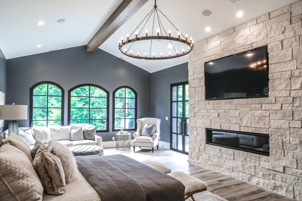 Источник вдохновения для домашнего уюта: большая хозяйская спальня в средиземноморском стиле с серыми стенами, полом из керамогранита, фасадом камина из камня, коричневым полом и горизонтальным камином