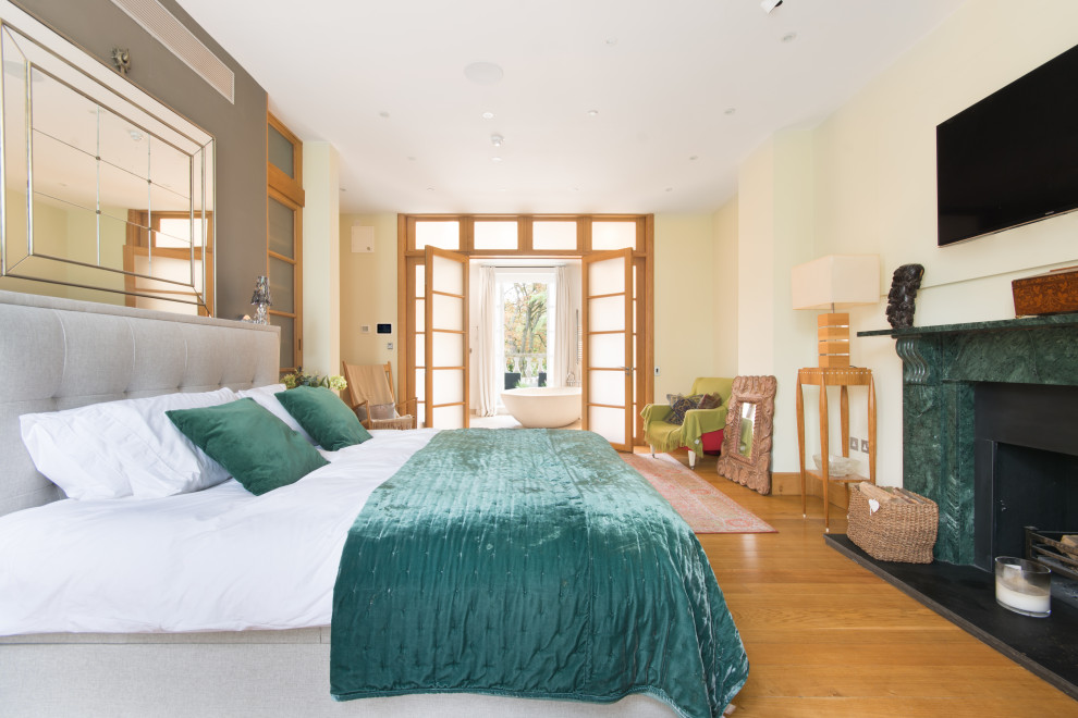Esempio di una camera da letto minimal con pareti beige, pavimento in legno massello medio, camino classico e pavimento marrone
