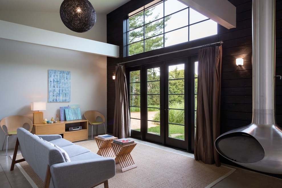 Стильный дизайн: гостевая спальня среднего размера, (комната для гостей) в стиле модернизм с белыми стенами, бетонным полом, подвесным камином, фасадом камина из металла и серым полом - последний тренд