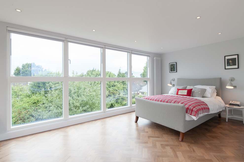 Modernes Hauptschlafzimmer ohne Kamin mit grauer Wandfarbe und hellem Holzboden in Surrey
