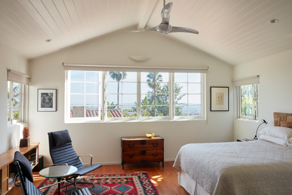 Foto på ett medelhavsstil sovrum, med vita väggar, mellanmörkt trägolv och brunt golv