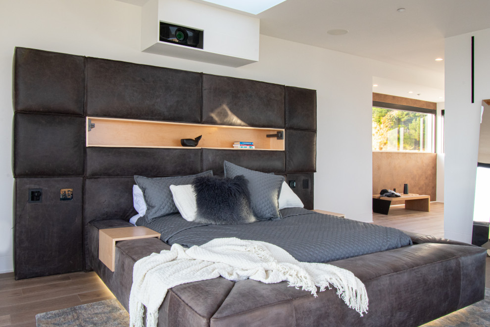 Example of an urban medium tone wood floor and brown floor bedroom design in Los Angeles with white walls