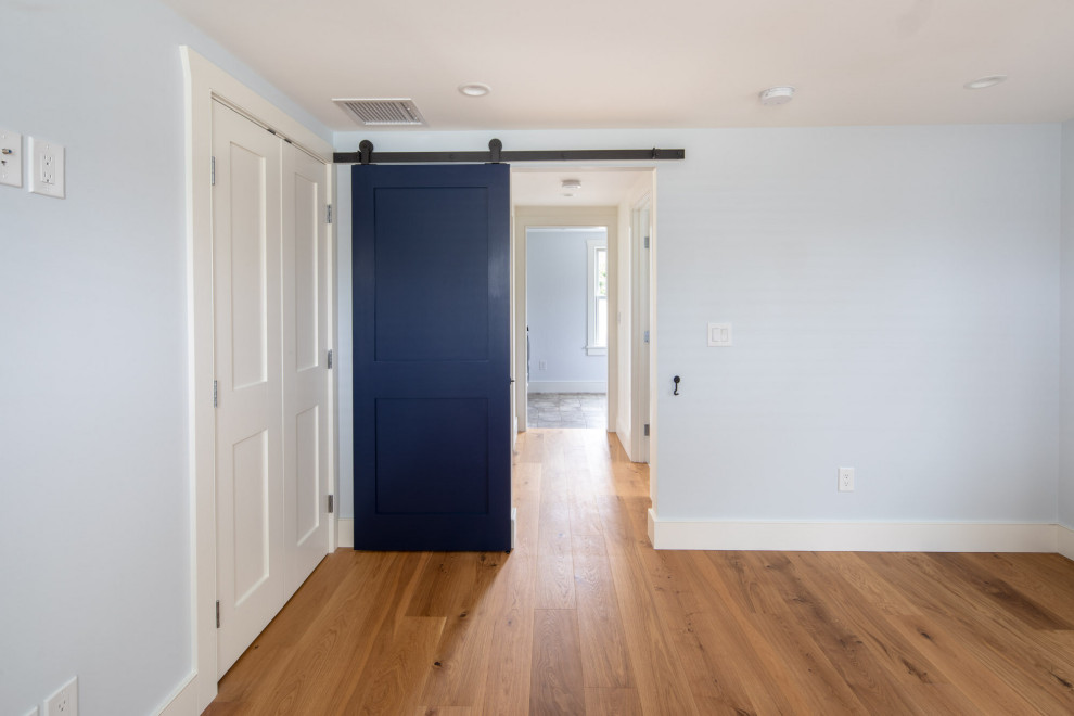 Foto di una piccola camera da letto stile marino con pareti blu, pavimento marrone e pavimento in legno massello medio