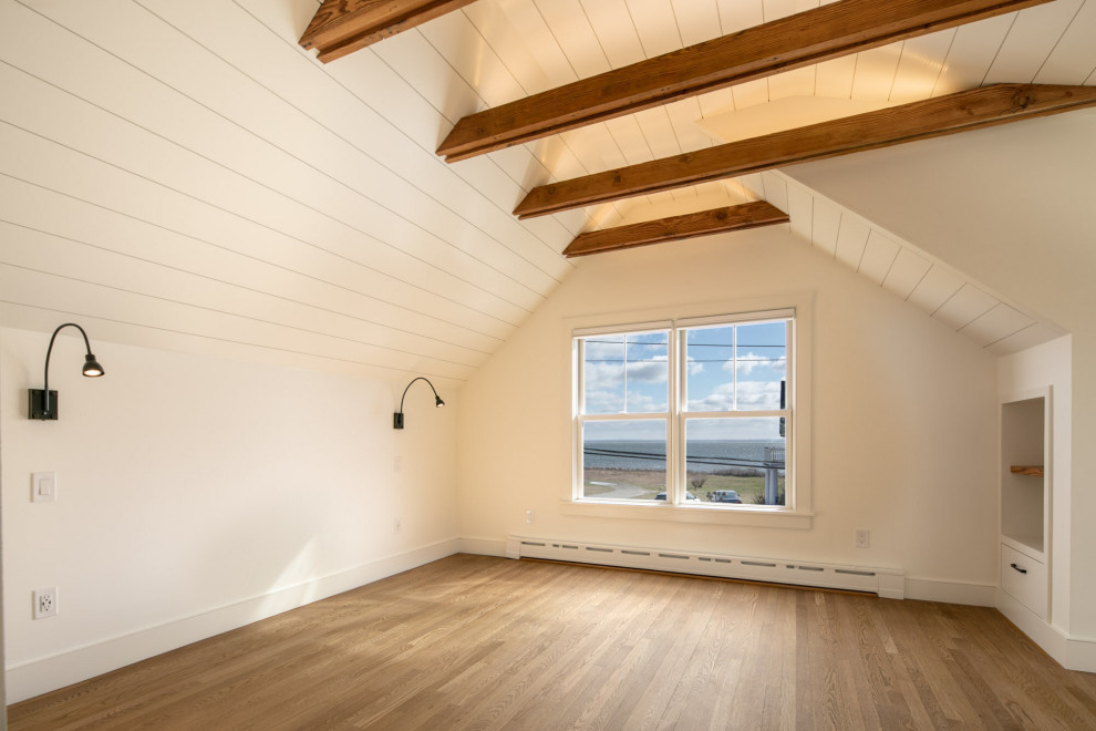 Cette image montre une petite chambre marine avec un mur blanc, aucune cheminée, un sol marron, poutres apparentes et un sol en bois brun.