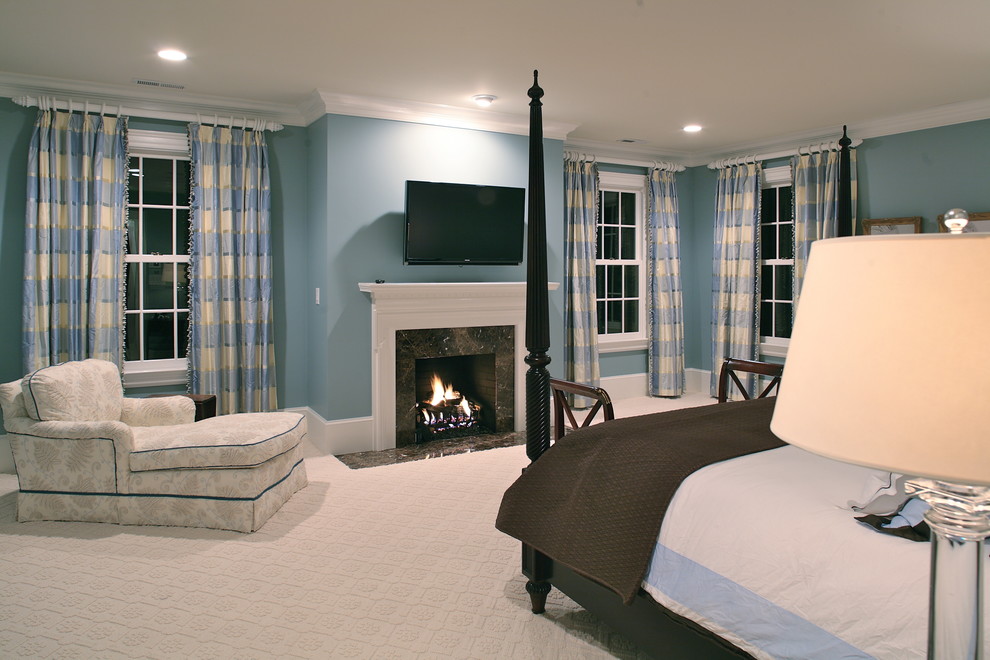 Cette image montre une grande chambre traditionnelle avec un mur bleu, une cheminée standard et un manteau de cheminée en pierre.
