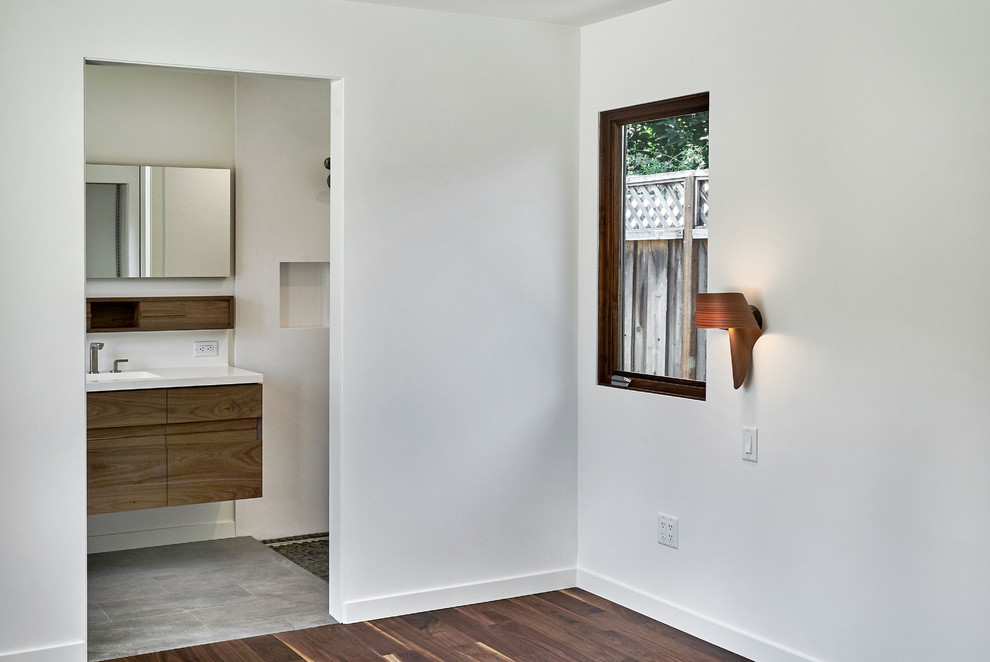 Diseño de dormitorio principal minimalista pequeño con paredes grises, suelo de madera en tonos medios y suelo marrón