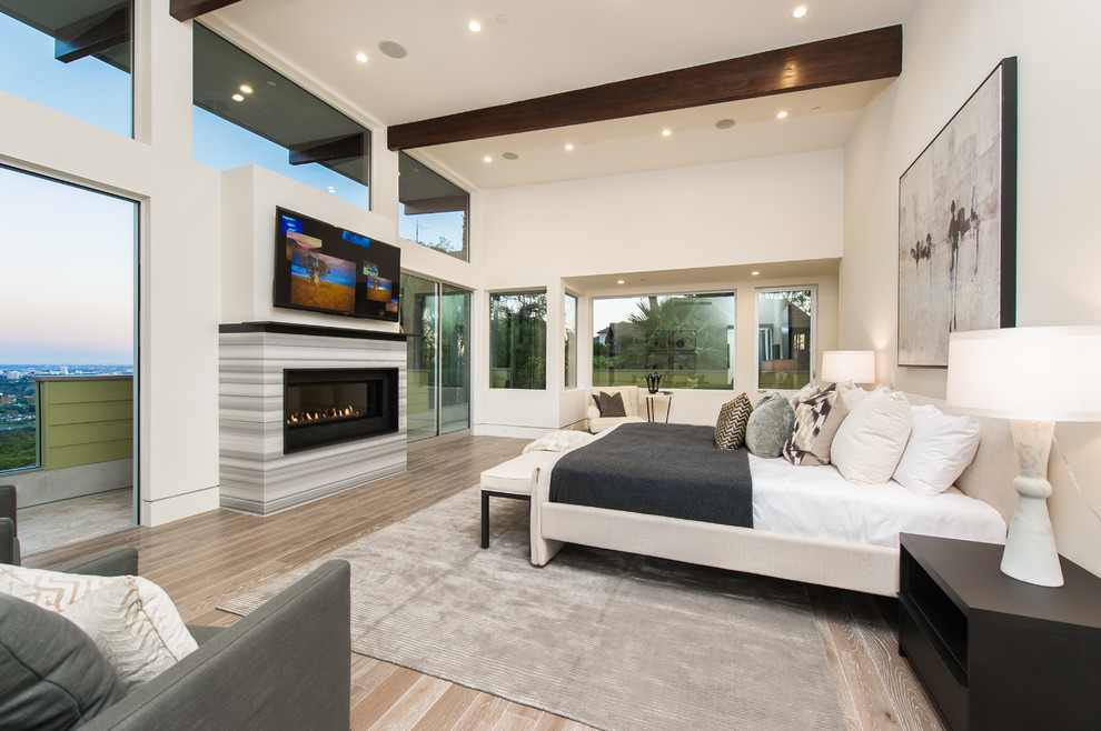 Large minimalist master light wood floor and brown floor bedroom photo in Los Angeles with white walls, a ribbon fireplace and a tile fireplace