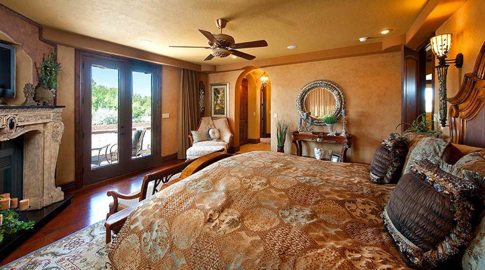 Пример оригинального дизайна: большая хозяйская спальня в викторианском стиле с бежевыми стенами, темным паркетным полом, угловым камином, фасадом камина из штукатурки и коричневым полом