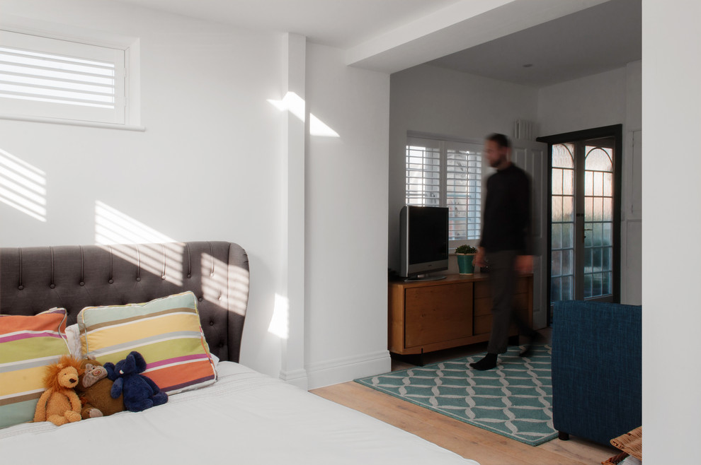 Mittelgroßes Modernes Gästezimmer mit weißer Wandfarbe, braunem Holzboden und braunem Boden in London