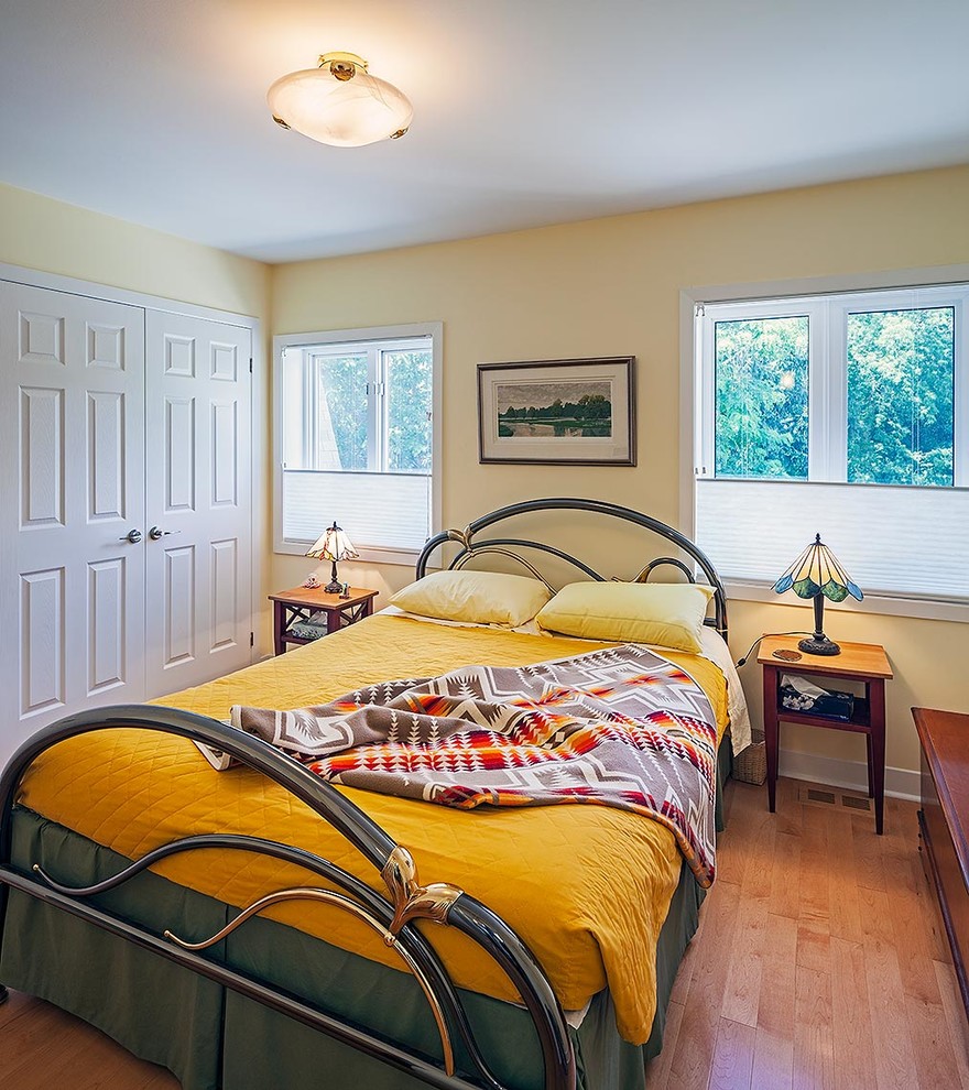 Imagen de dormitorio tradicional renovado con paredes amarillas y suelo de madera en tonos medios