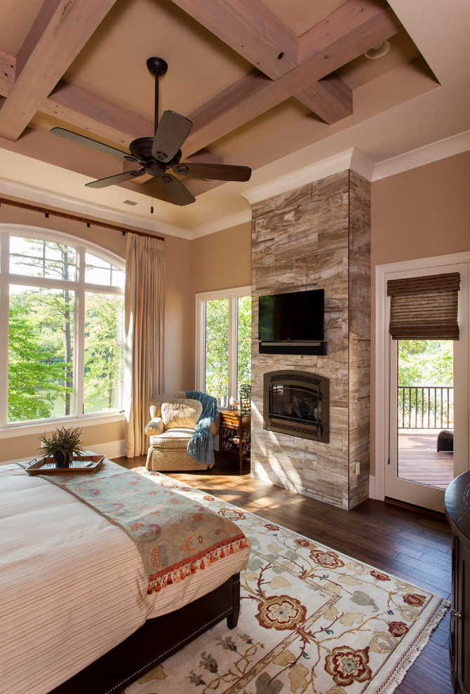 Großes Uriges Hauptschlafzimmer mit beiger Wandfarbe, dunklem Holzboden, Kamin, gefliester Kaminumrandung und braunem Boden in Charlotte