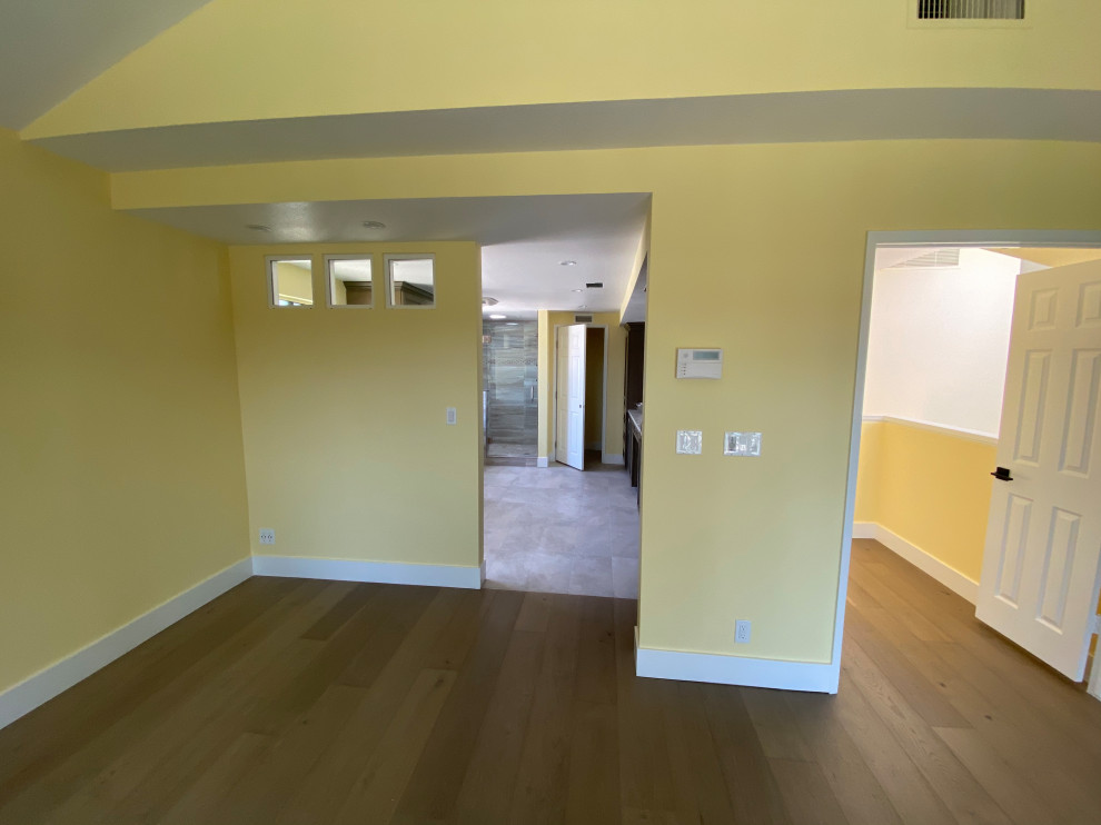Foto di una grande camera degli ospiti minimal con pareti gialle, parquet chiaro, nessun camino e pavimento marrone
