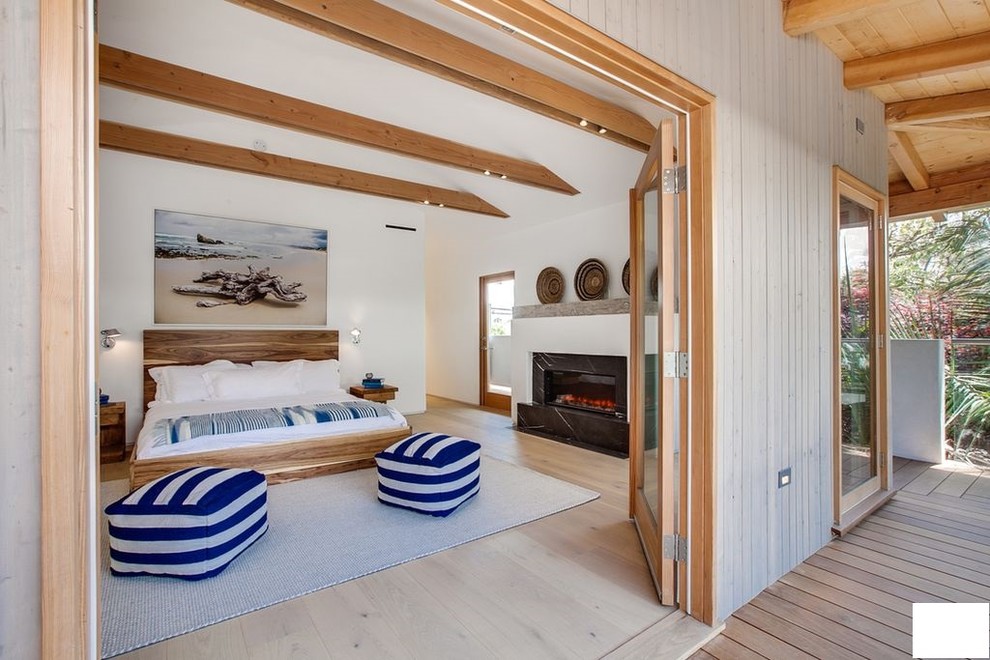 Großes Asiatisches Hauptschlafzimmer mit weißer Wandfarbe, hellem Holzboden, Kamin, Kaminumrandung aus Stein und beigem Boden in Los Angeles
