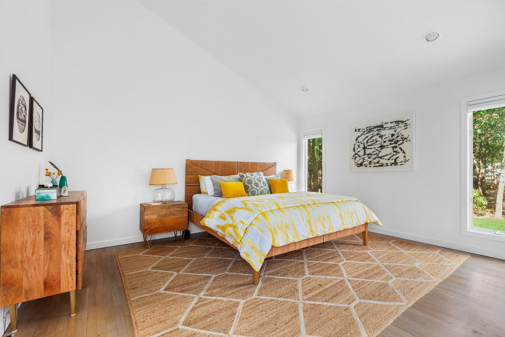 Imagen de dormitorio abovedado costero con paredes blancas, suelo de madera en tonos medios y suelo marrón