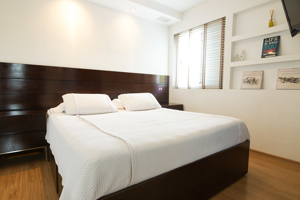 Modelo de dormitorio principal actual pequeño con paredes blancas, suelo laminado y suelo marrón