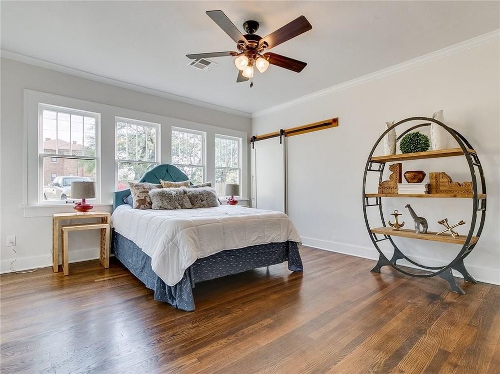 Example of an eclectic medium tone wood floor and brown floor bedroom design in Oklahoma City with white walls
