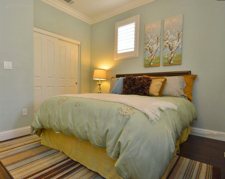 Modelo de habitación de invitados clásica de tamaño medio sin chimenea con suelo de madera oscura, suelo marrón y paredes grises