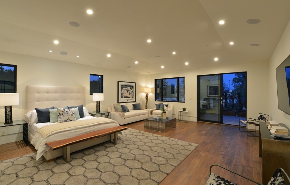 This is an example of an expansive contemporary master bedroom in Los Angeles with white walls, medium hardwood flooring, no fireplace and brown floors.