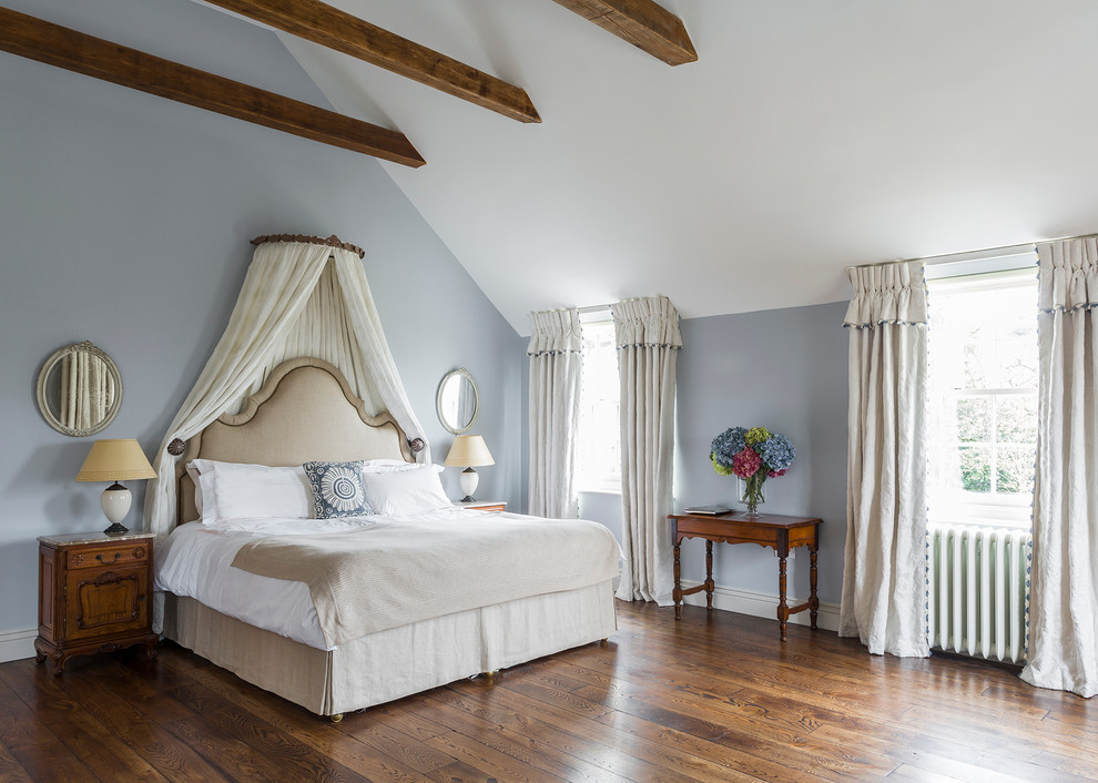 Elegant medium tone wood floor bedroom photo in Kent with blue walls