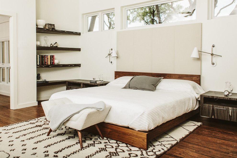 This is an example of a midcentury bedroom in Austin with white walls and medium hardwood flooring.