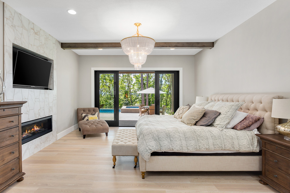 Modelo de dormitorio televisión tradicional renovado con paredes grises, suelo de madera clara, chimenea lineal, marco de chimenea de baldosas y/o azulejos y suelo beige