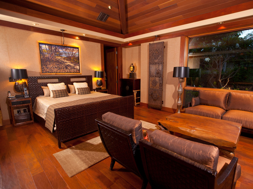 Esempio di una camera matrimoniale tropicale con pareti beige e pavimento in legno massello medio