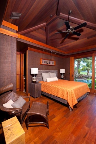 Foto di una camera degli ospiti tropicale con pareti viola e pavimento in legno massello medio