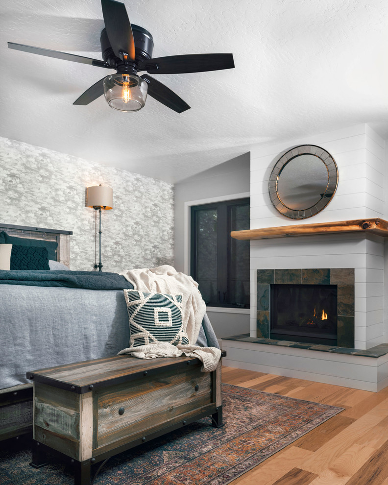 サクラメントにある中くらいなカントリー風のおしゃれな主寝室 (グレーの壁、無垢フローリング、標準型暖炉、木材の暖炉まわり、茶色い床)