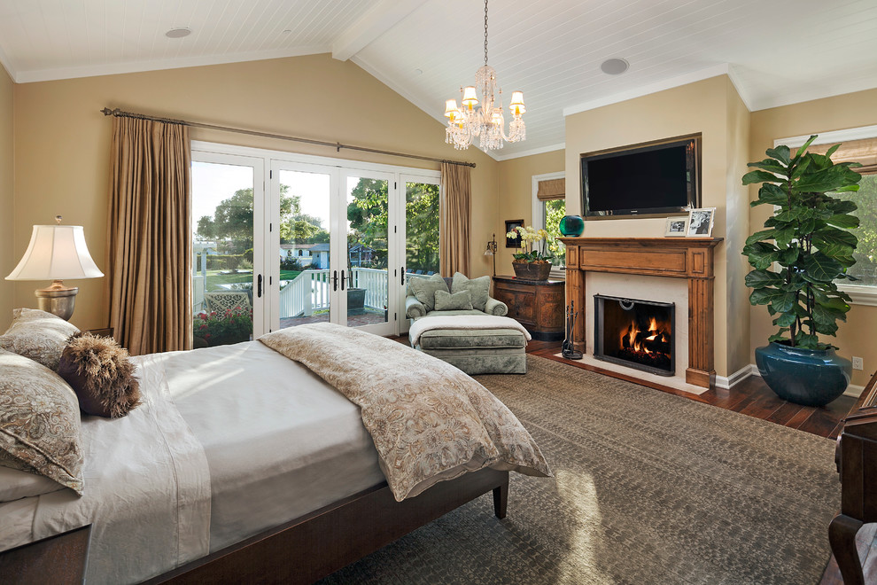 サンタバーバラにある中くらいなトラディショナルスタイルのおしゃれな主寝室 (ベージュの壁、濃色無垢フローリング、標準型暖炉、木材の暖炉まわり) のインテリア