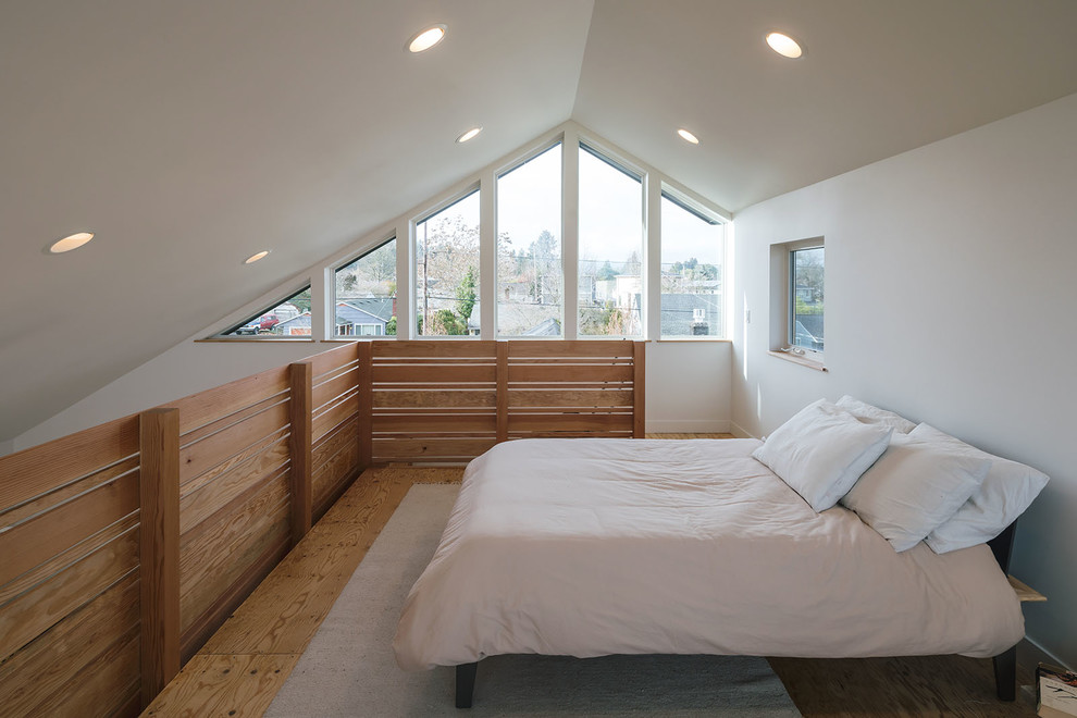 Imagen de dormitorio tipo loft moderno de tamaño medio con paredes blancas y suelo de contrachapado
