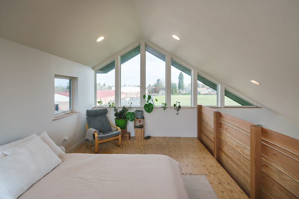 This is an example of a medium sized modern mezzanine bedroom in Portland with white walls and plywood flooring.