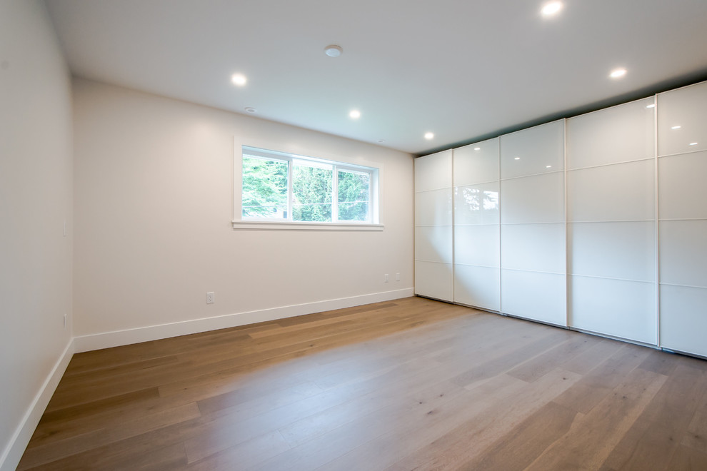 Geräumiges Modernes Hauptschlafzimmer ohne Kamin mit weißer Wandfarbe und braunem Holzboden in Vancouver