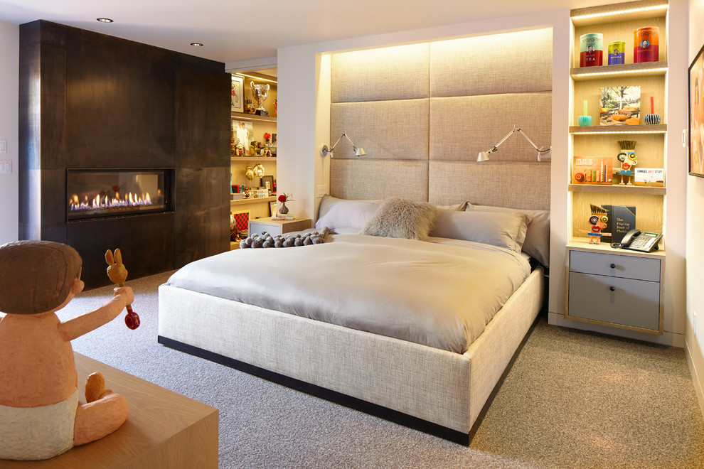Modelo de dormitorio contemporáneo con paredes blancas, moqueta, chimenea lineal, marco de chimenea de metal y suelo gris