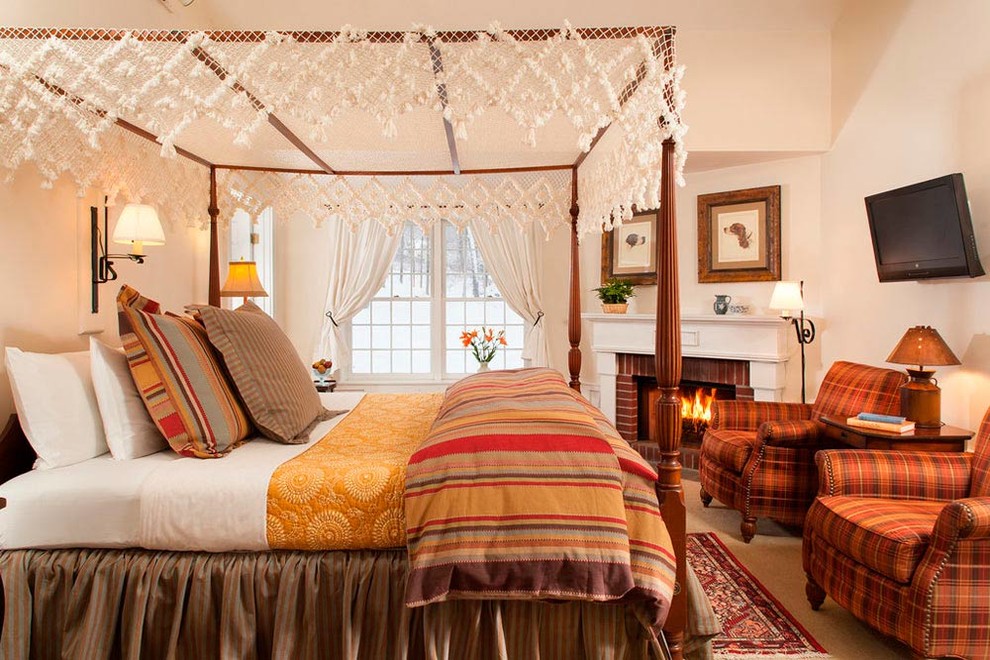 Imagen de dormitorio televisión tradicional con paredes beige, todas las chimeneas y marco de chimenea de ladrillo