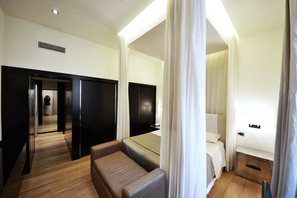 Immagine di una grande camera matrimoniale design con pareti bianche e pavimento in legno massello medio