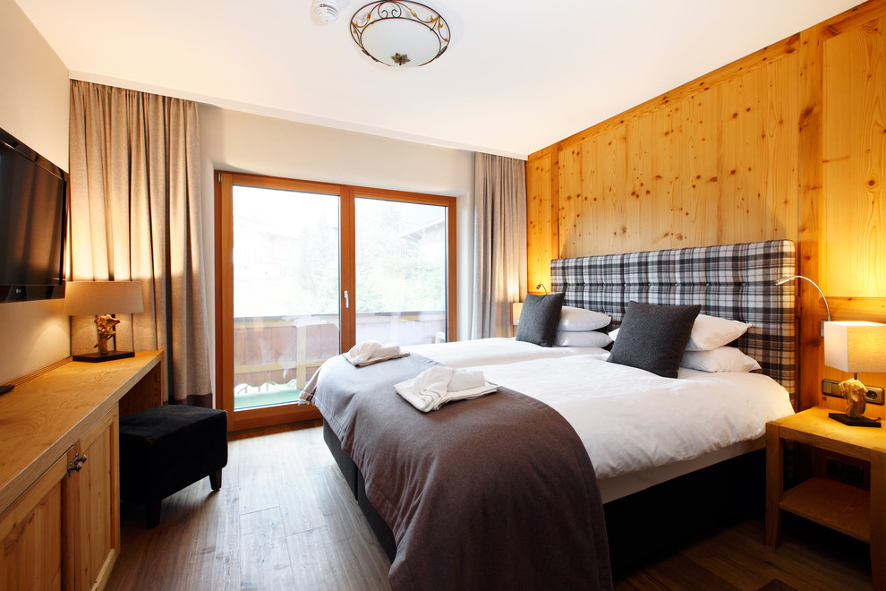 Ejemplo de habitación de invitados rural de tamaño medio con paredes beige y suelo de madera oscura
