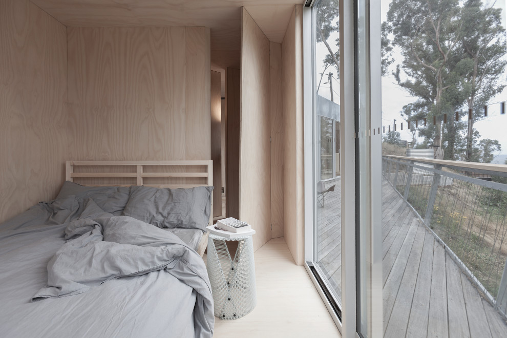 Imagen de dormitorio nórdico con paredes beige y suelo de contrachapado