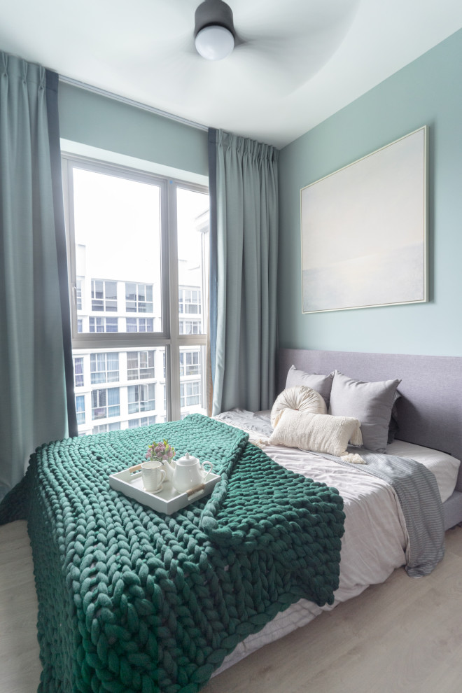 Modernes Schlafzimmer mit blauer Wandfarbe, hellem Holzboden und beigem Boden in Singapur