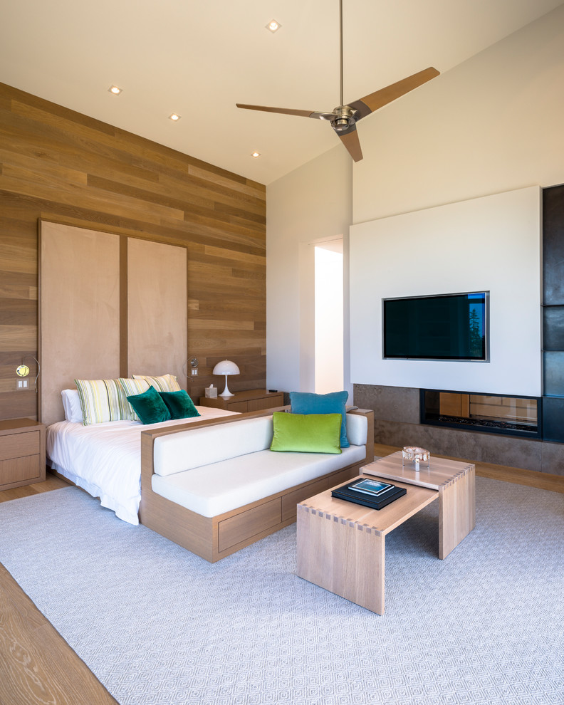 Großes Modernes Hauptschlafzimmer mit weißer Wandfarbe, braunem Holzboden, Tunnelkamin, braunem Boden und Kaminumrandung aus Stein in Toronto