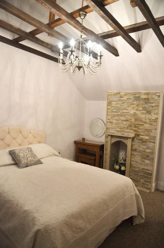 Mittelgroßes Uriges Hauptschlafzimmer mit weißer Wandfarbe, Teppichboden, Kamin und gefliester Kaminumrandung in Sonstige