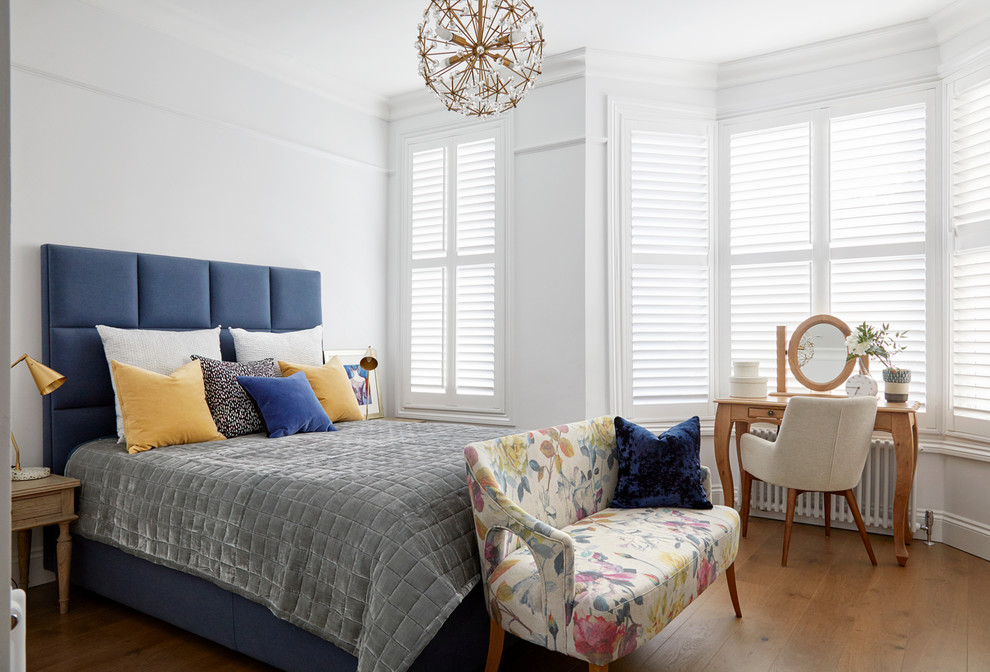Klassisches Gästezimmer mit weißer Wandfarbe, braunem Holzboden und braunem Boden in London