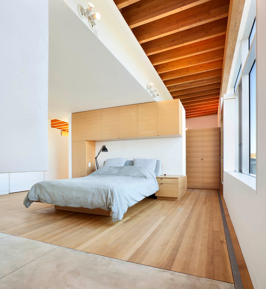 Modelo de dormitorio principal y blanco y madera actual de tamaño medio con paredes blancas y suelo de madera clara